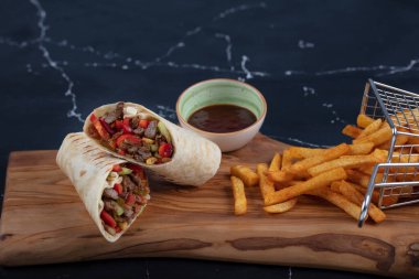 Et ambalajı; Türkçe adı, Et Durum. Yumuşak dilimlenmiş biftek, kırmızı biber ve salata süslemeleri ile kaplı tortilla, arka planda fotokopi alanı ile kaplanmış.