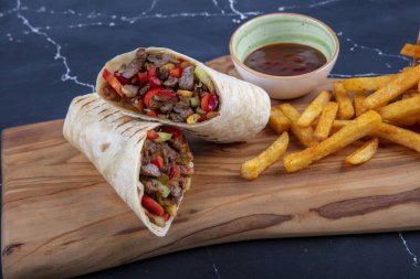 Et ambalajı; Türkçe adı, Et Durum. Yumuşak dilimlenmiş biftek, kırmızı biber ve salata süslemeleri ile kaplı tortilla, arka planda fotokopi alanı ile kaplanmış.