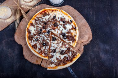 Etli İtalyan pizzası, biftek dilimleri, erimiş peynir, zeytin dilimleri ve çedar peyniri. Yaklaş, makro. Pizza zamanı konsepti. Türkçe adı: Kavurmali Pizza.