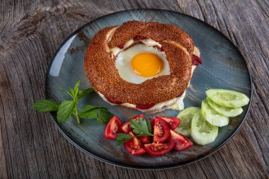 Çörek, yumurta, salatalık ve domateslerden oluşan lezzetli bir kahvaltı tabağı..