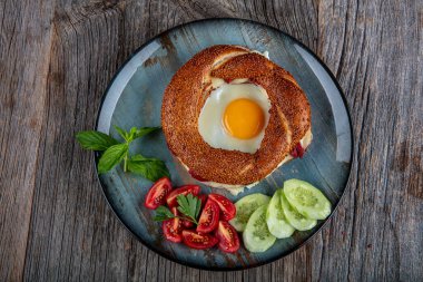 Çörek, yumurta, salatalık ve domateslerden oluşan lezzetli bir kahvaltı tabağı..
