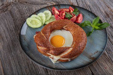 Çörek, yumurta, salatalık ve domateslerden oluşan lezzetli bir kahvaltı tabağı..