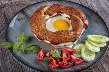 Çörek, yumurta, salatalık ve domateslerden oluşan lezzetli bir kahvaltı tabağı..