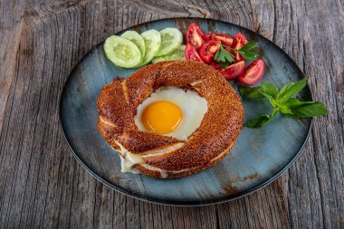 Çörek, yumurta, salatalık ve domateslerden oluşan lezzetli bir kahvaltı tabağı..