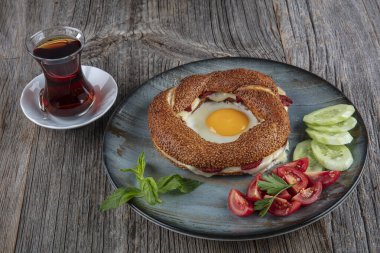 Çörek, yumurta, salatalık ve domateslerden oluşan lezzetli bir kahvaltı tabağı..