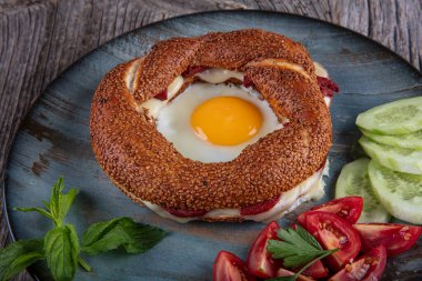 Çörek, yumurta, salatalık ve domateslerden oluşan lezzetli bir kahvaltı tabağı..