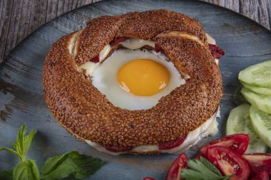 Çörek, yumurta, salatalık ve domateslerden oluşan lezzetli bir kahvaltı tabağı..