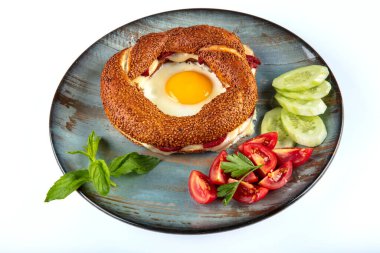 Çörek, yumurta, salatalık ve domateslerden oluşan lezzetli bir kahvaltı tabağı..