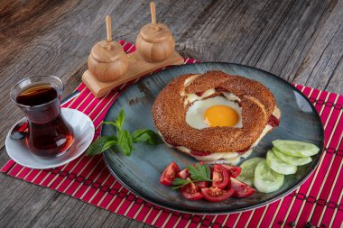 Çörek, yumurta, salatalık ve domateslerden oluşan lezzetli bir kahvaltı tabağı..