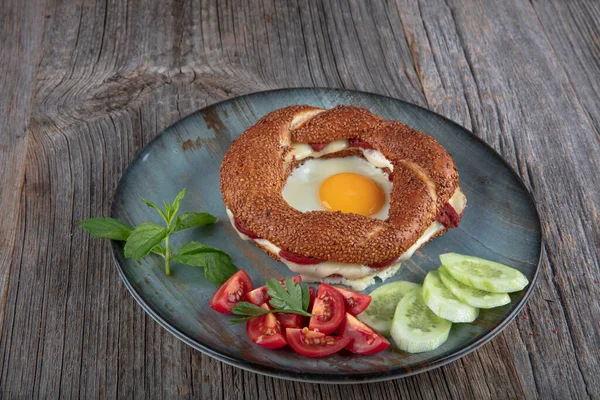 Çörek, yumurta, salatalık ve domateslerden oluşan lezzetli bir kahvaltı tabağı..