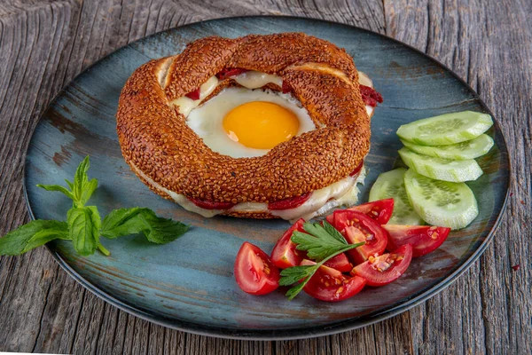 Çörek, yumurta, salatalık ve domateslerden oluşan lezzetli bir kahvaltı tabağı..