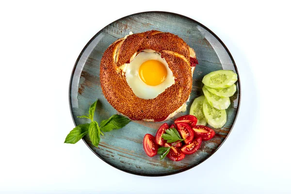 Çörek, yumurta, salatalık ve domateslerden oluşan lezzetli bir kahvaltı tabağı..