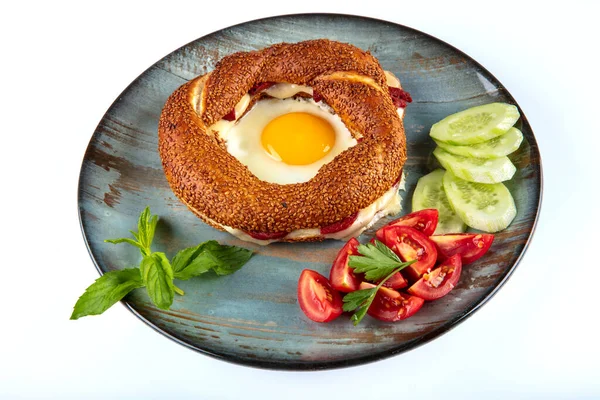 Çörek, yumurta, salatalık ve domateslerden oluşan lezzetli bir kahvaltı tabağı..