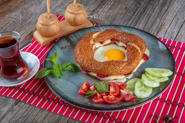 Çörek, yumurta, salatalık ve domateslerden oluşan lezzetli bir kahvaltı tabağı..