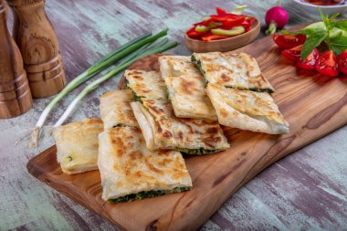 Taze pişmiş Türk tortillası - Tahta üzerinde ıspanaklı Gözleme ve Türk çayı. Mesaj için yer var. Yüzeyin derinliği. El yapımı Türk geleneksel pastaları.