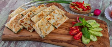 Taze pişmiş Türk tortillası - Tahta üzerinde ıspanaklı Gözleme ve Türk çayı. Mesaj için yer var. Yüzeyin derinliği. El yapımı Türk geleneksel pastaları.