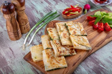 Taze pişmiş Türk tortillası - Tahta üzerinde ıspanaklı Gözleme ve Türk çayı. Mesaj için yer var. Yüzeyin derinliği. El yapımı Türk geleneksel pastaları.