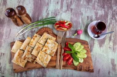 Taze pişmiş Türk tortillası - Tahta üzerinde ıspanaklı Gözleme ve Türk çayı. Mesaj için yer var. Yüzeyin derinliği. El yapımı Türk geleneksel pastaları.