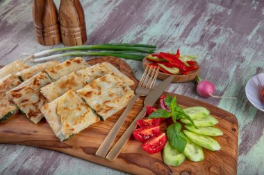 Taze pişmiş Türk tortillası - Tahta üzerinde ıspanaklı Gözleme ve Türk çayı. Mesaj için yer var. Yüzeyin derinliği. El yapımı Türk geleneksel pastaları.