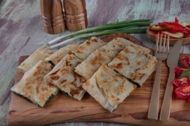 Taze pişmiş Türk tortillası - Tahta üzerinde ıspanaklı Gözleme ve Türk çayı. Mesaj için yer var. Yüzeyin derinliği. El yapımı Türk geleneksel pastaları.