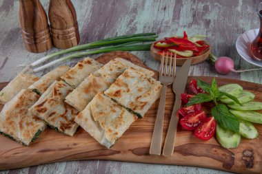 Taze pişmiş Türk tortillası - Tahta üzerinde ıspanaklı Gözleme ve Türk çayı. Mesaj için yer var. Yüzeyin derinliği. El yapımı Türk geleneksel pastaları.