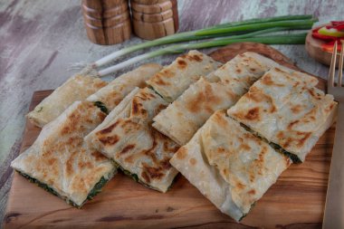 Taze pişmiş Türk tortillası - Tahta üzerinde ıspanaklı Gözleme ve Türk çayı. Mesaj için yer var. Yüzeyin derinliği. El yapımı Türk geleneksel pastaları.