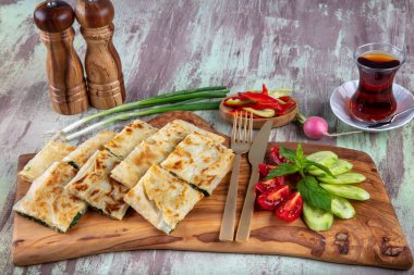 Taze pişmiş Türk tortillası - Tahta üzerinde ıspanaklı Gözleme ve Türk çayı. Mesaj için yer var. Yüzeyin derinliği. El yapımı Türk geleneksel pastaları.