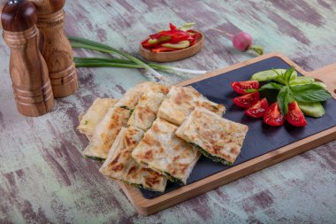 Taze pişmiş Türk tortillası - Tahta üzerinde ıspanaklı Gözleme ve Türk çayı. Mesaj için yer var. Yüzeyin derinliği. El yapımı Türk geleneksel pastaları.