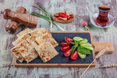 Taze pişmiş Türk tortillası - Tahta üzerinde ıspanaklı Gözleme ve Türk çayı. Mesaj için yer var. Yüzeyin derinliği. El yapımı Türk geleneksel pastaları.