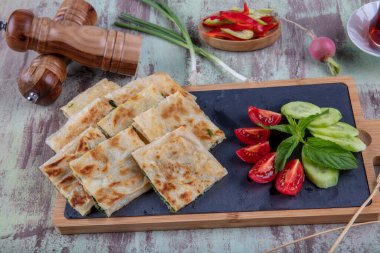 Taze pişmiş Türk tortillası - Tahta üzerinde ıspanaklı Gözleme ve Türk çayı. Mesaj için yer var. Yüzeyin derinliği. El yapımı Türk geleneksel pastaları.