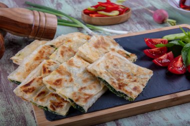 Taze pişmiş Türk tortillası - Tahta üzerinde ıspanaklı Gözleme ve Türk çayı. Mesaj için yer var. Yüzeyin derinliği. El yapımı Türk geleneksel pastaları.