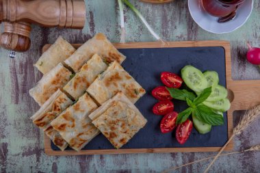 Taze pişmiş Türk tortillası - Tahta üzerinde ıspanaklı Gözleme ve Türk çayı. Mesaj için yer var. Yüzeyin derinliği. El yapımı Türk geleneksel pastaları.