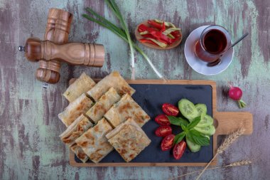 Taze pişmiş Türk tortillası - Tahta üzerinde ıspanaklı Gözleme ve Türk çayı. Mesaj için yer var. Yüzeyin derinliği. El yapımı Türk geleneksel pastaları.