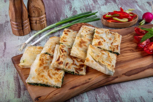 Taze pişmiş Türk tortillası - Tahta üzerinde ıspanaklı Gözleme ve Türk çayı. Mesaj için yer var. Yüzeyin derinliği. El yapımı Türk geleneksel pastaları.