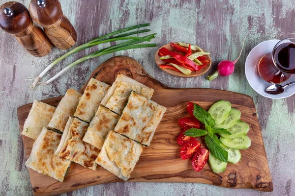 Taze pişmiş Türk tortillası - Tahta üzerinde ıspanaklı Gözleme ve Türk çayı. Mesaj için yer var. Yüzeyin derinliği. El yapımı Türk geleneksel pastaları.