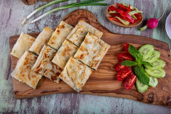 Taze pişmiş Türk tortillası - Tahta üzerinde ıspanaklı Gözleme ve Türk çayı. Mesaj için yer var. Yüzeyin derinliği. El yapımı Türk geleneksel pastaları.