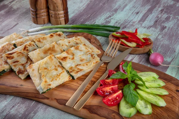 Taze pişmiş Türk tortillası - Tahta üzerinde ıspanaklı Gözleme ve Türk çayı. Mesaj için yer var. Yüzeyin derinliği. El yapımı Türk geleneksel pastaları.