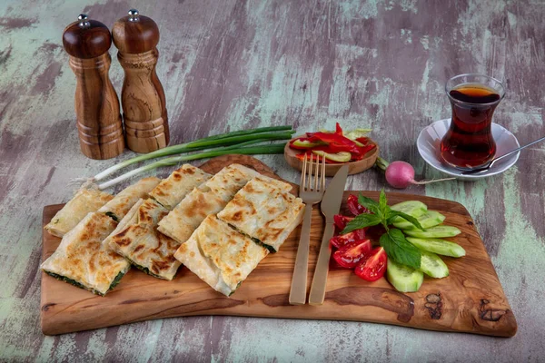 Taze pişmiş Türk tortillası - Tahta üzerinde ıspanaklı Gözleme ve Türk çayı. Mesaj için yer var. Yüzeyin derinliği. El yapımı Türk geleneksel pastaları.