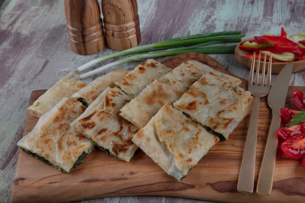 Taze pişmiş Türk tortillası - Tahta üzerinde ıspanaklı Gözleme ve Türk çayı. Mesaj için yer var. Yüzeyin derinliği. El yapımı Türk geleneksel pastaları.