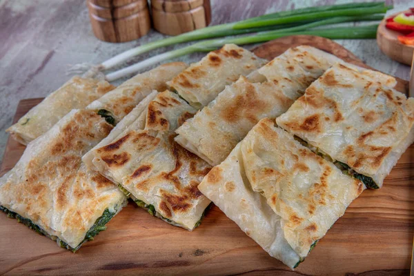 Taze pişmiş Türk tortillası - Tahta üzerinde ıspanaklı Gözleme ve Türk çayı. Mesaj için yer var. Yüzeyin derinliği. El yapımı Türk geleneksel pastaları.