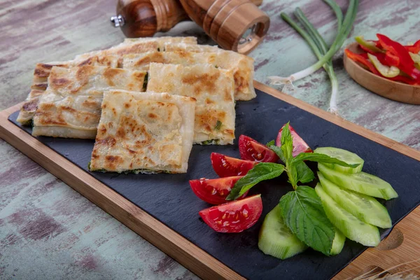 Taze pişmiş Türk tortillası - Tahta üzerinde ıspanaklı Gözleme ve Türk çayı. Mesaj için yer var. Yüzeyin derinliği. El yapımı Türk geleneksel pastaları.