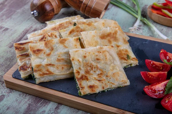 Taze pişmiş Türk tortillası - Tahta üzerinde ıspanaklı Gözleme ve Türk çayı. Mesaj için yer var. Yüzeyin derinliği. El yapımı Türk geleneksel pastaları.