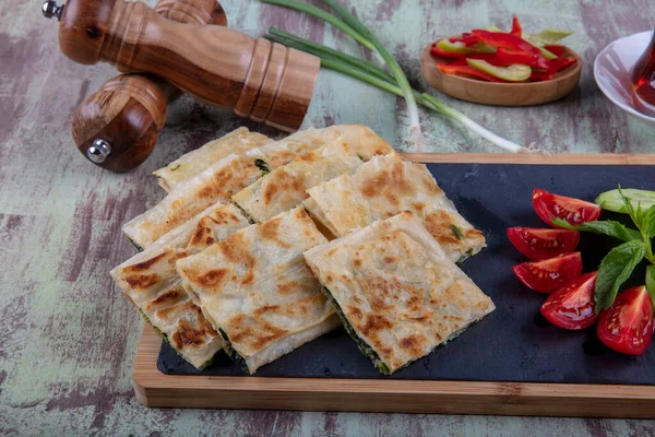 Taze pişmiş Türk tortillası - Tahta üzerinde ıspanaklı Gözleme ve Türk çayı. Mesaj için yer var. Yüzeyin derinliği. El yapımı Türk geleneksel pastaları.