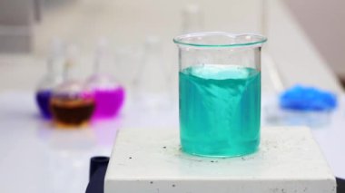Cyan solution in a beaker is agitated with magnetic stirred in the laboratory