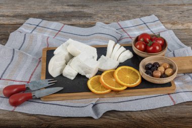 Tam yağlı inek peyniri. Kesme tahtasındaki taze peynir. Beş kiloluk plastik bir kapta beyaz peynir. Yiyecek konsepti.