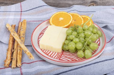 Kashar Peynir Tabağı. Ahşap bir arka planda çedar peyniri ya da kaşar peyniri. Servis tabağında peynir dilimleri.