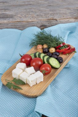 Taze yağlı beyaz peynir. Tahta tezgahta doğranmış peynir ve vişneli domates. Yan görünüm, seçici odak.  