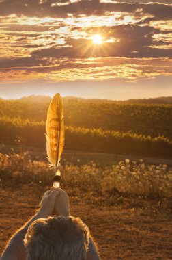 Gün batımında altın ışıkla tüy tutan adam.