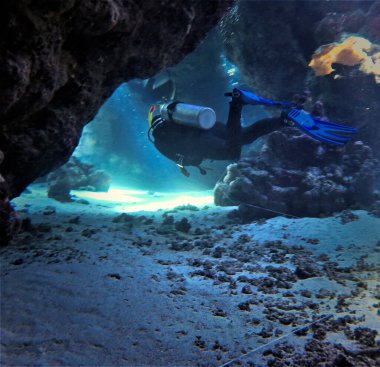 Mağaranın içinde güneş ışığı ve ışınlar olan su altı manzarası. Mısır 'daki Kızıl Deniz' deki bir dalıştan..