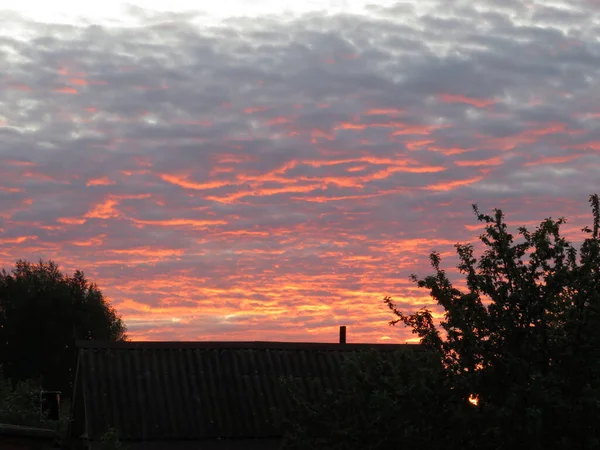 Färgglad solnedgång med moln och taket på huset — Stockfoto